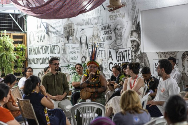 Liderança indígena discursa ao microfone durante painel na Casa da COP do Povo, em Belém, evento paralelo à COP30 realizado pela Global Witness e pelo Instituto Zé Cláudio e Maria, com interpretação simultânea da W2 Simultânea.